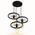 Industrial-style three-light pendant ceiling fixture with three black wheel-shaped shades and exposed warm-white Edison bulbs, suspended from a round black ceiling canopy on a white background.
