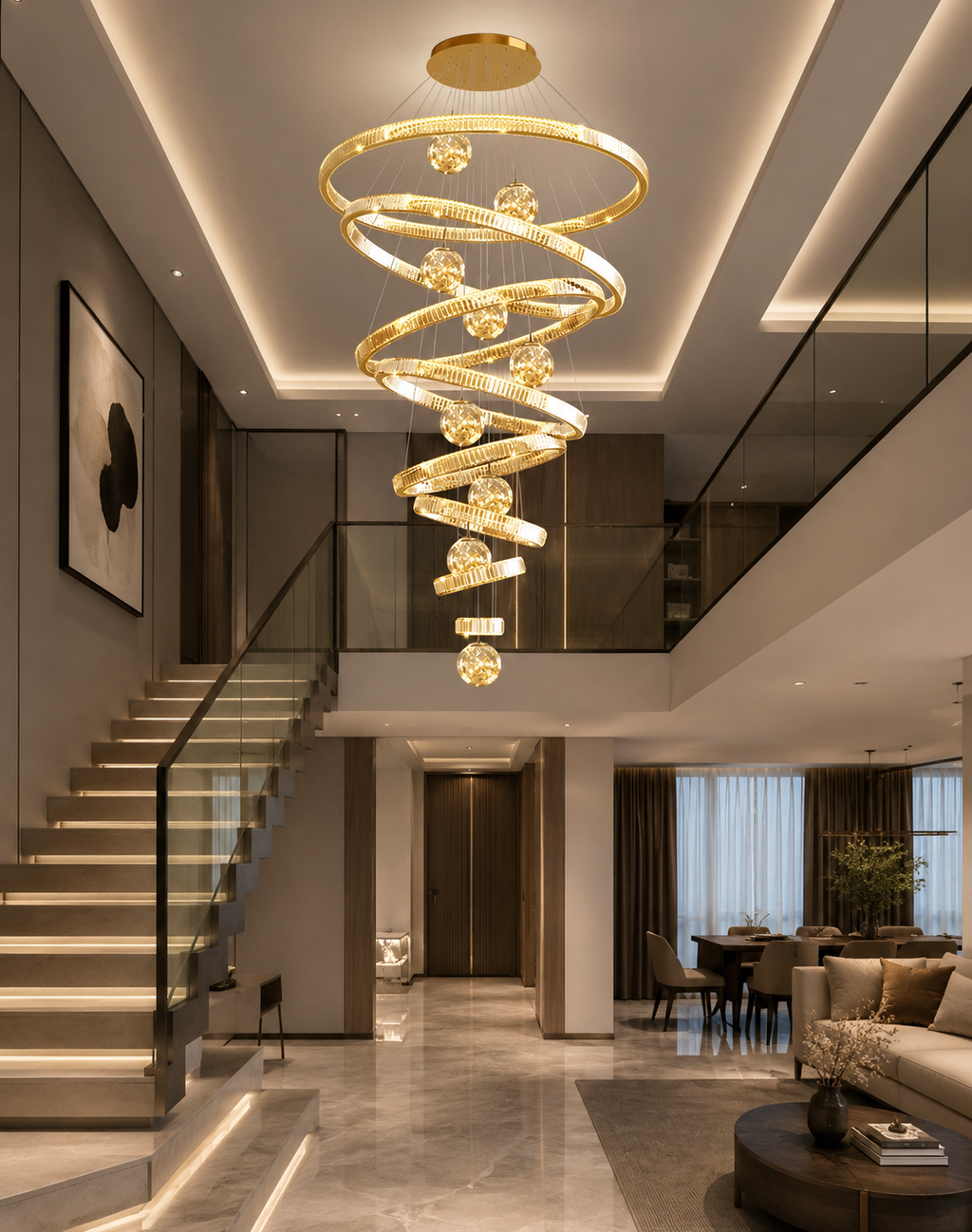 A modern spiral chandelier with gold-toned rings and clear crystal-like accents hangs in a spacious, contemporary home entryway with a staircase, dining area, and living room visible below.