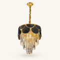 A gold and black chandelier pendant light with clear crystal drops, suspended from a twisted gold rod against a light beige background.